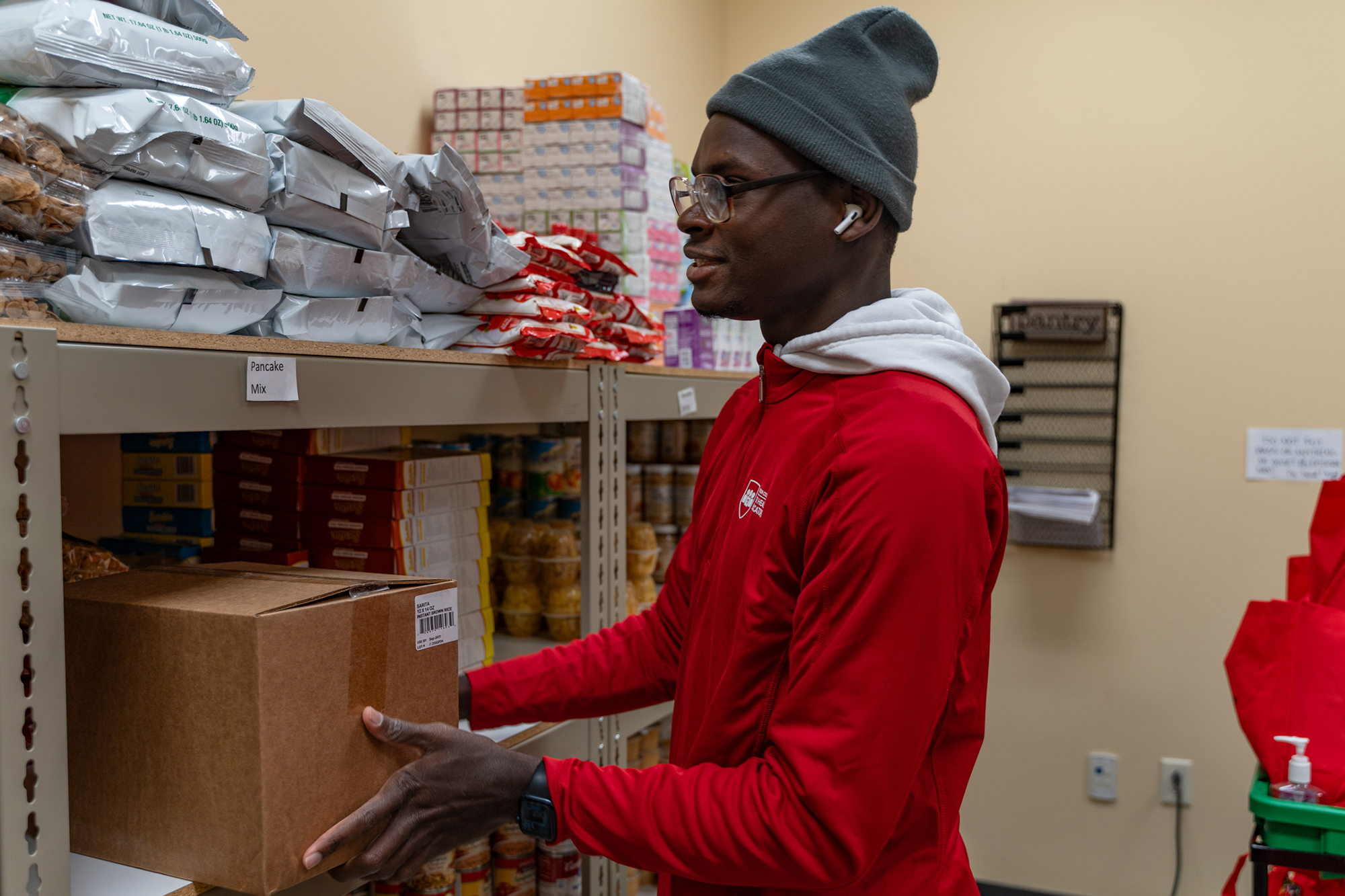 Jovhany Michaud puts food items away while working at the college's food pantry on Tuesday, Oct. 15, 2024. 