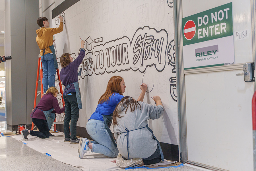 Students work on a mural outside the blocked off Student Services area that is under construction through August 2025.